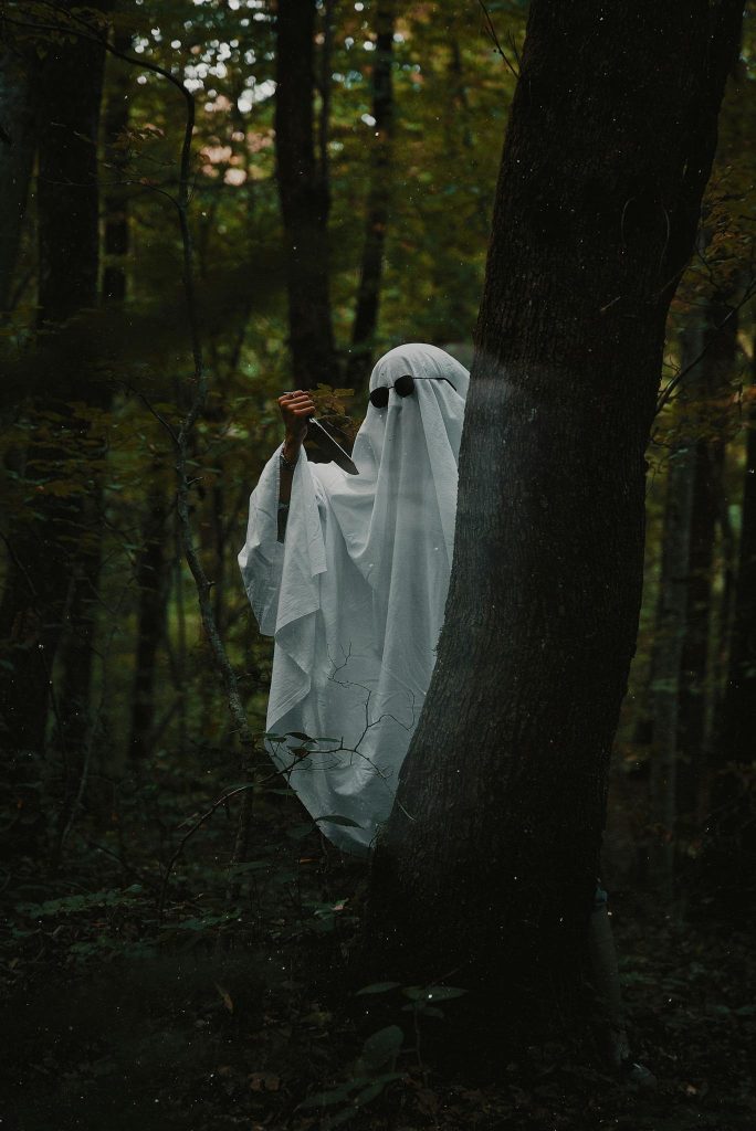 A ghostly figure holding a book in a dark forest, creating an eerie atmosphere.